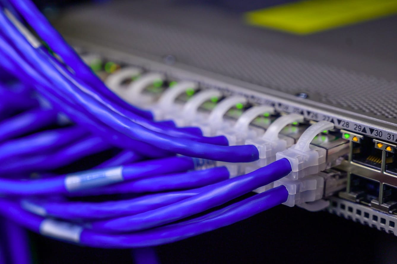 Cabos de rede conectados a um switch em rack de equipamentos